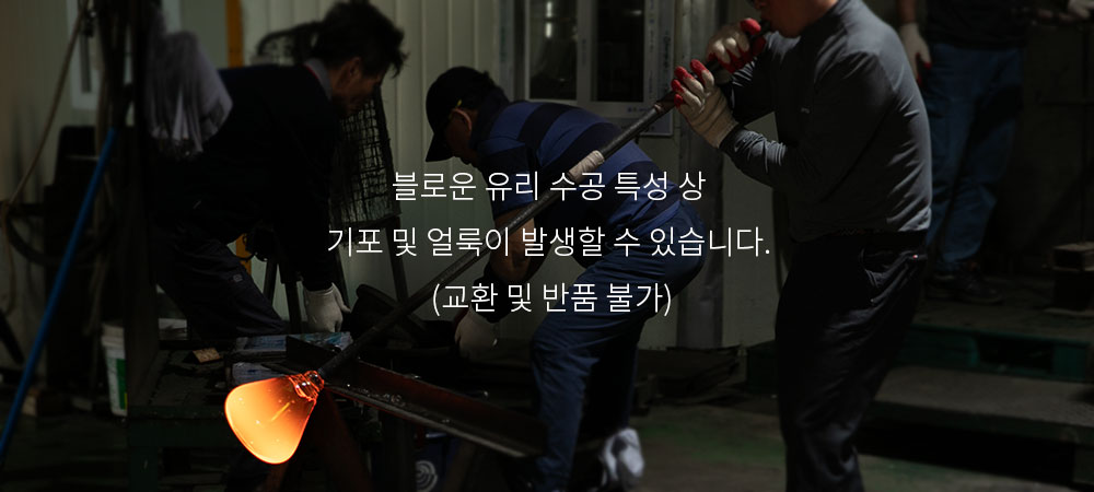 주방식탁조명과 같은 유리 펜던트조명이 제작되는 과정으로, 장인이 뜨겁게 가열된 유리를 블로잉 기법으로 정교하게 가공하는 장면. 주황빛으로 빛나는 유리가 작업자의 섬세한 손길 아래 형태를 잡아가고 있으며, 블로운 유리 수공 특성상 기포 및 얼룩이 발생할 수 있습니다. (교환 및 반품 불가) 라는 안내 문구가 포함됨.
