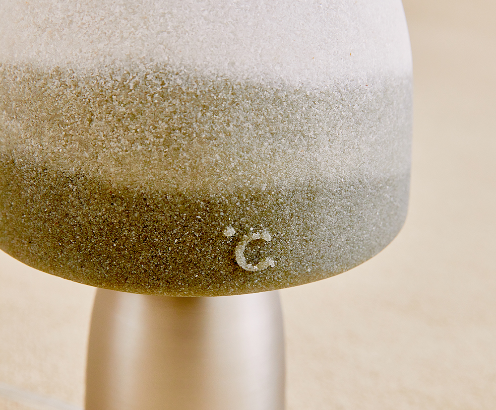 램프의 갓 표면이 모래로 만든 것처럼 거친 느낌이 찍힌 모습이다. 갓의 한 구석엔 도씨가 양각으로 새겨져있다. 