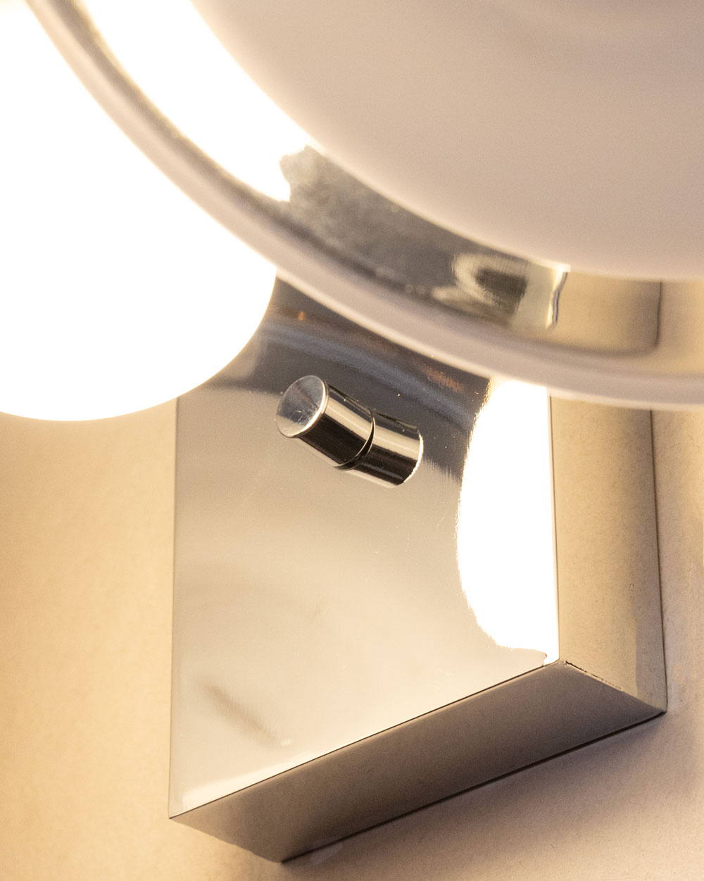 벽부등 측면 클로즈업으로 크롬 베이스와 투명 디스크 연결부가 견고하게 설계되어 고급스러운 벽조명 디테일을 보여줍니다.